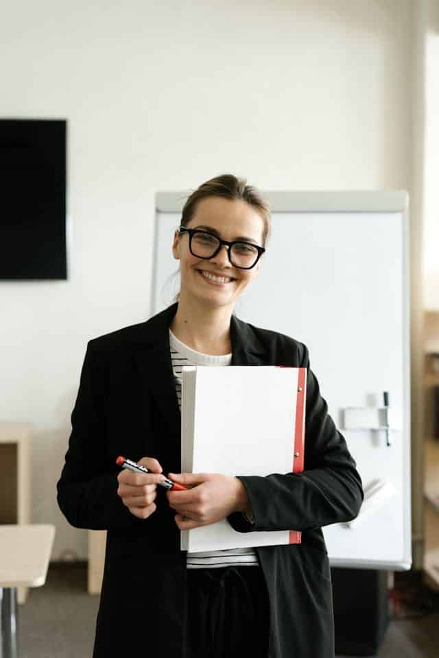 Portrait d'une jeune femme souriante tenant un classeur, symbolisant l'aisance acquise après une année Au Pair