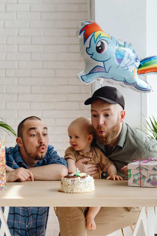 Famille d'accueil homoparentale fêtant l’anniversaire de leur enfant autour d’un gâteau, symbole d’un foyer américain accueillant